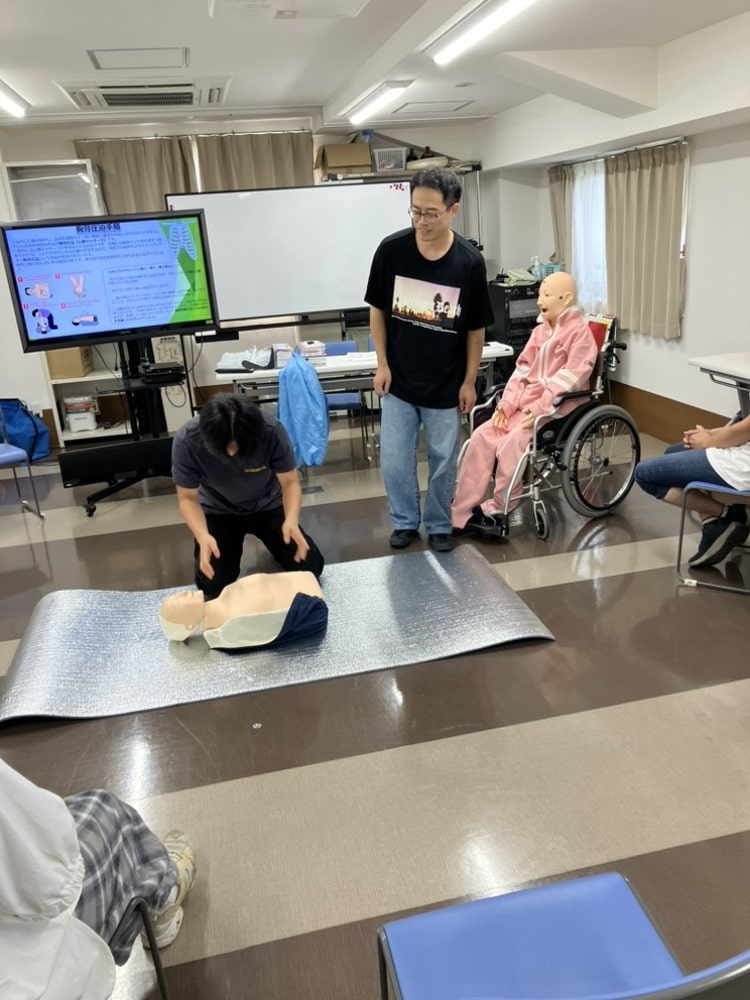 心臓マッサージの練習をする介助者